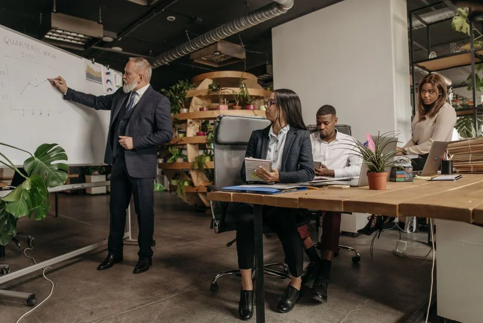 Person analyzes stock data with a smartphone and laptop, indoors.